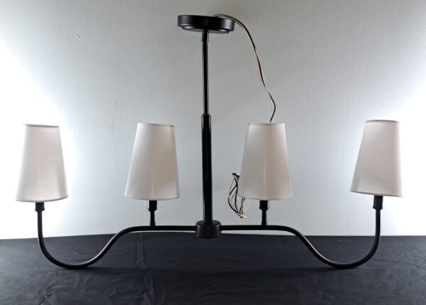 Matte black 4-light island pendant fixture with white linen shades shown out of the box on a tabletop.