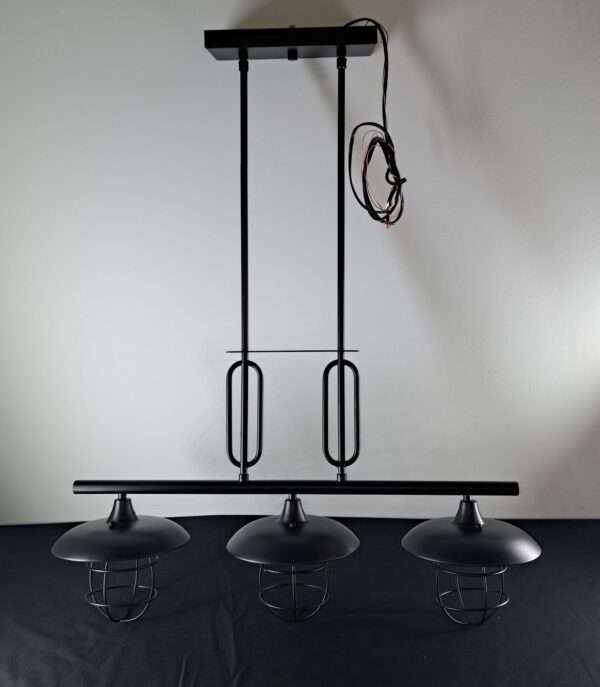 Black 3-light industrial island pendant with metal dome shades and wire cage guards, shown out of the box on a tabletop.
