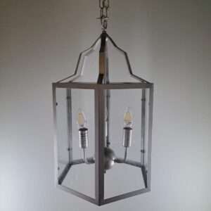Silver lantern-style foyer pendant hanging from a chain with clear glass panels and three candelabra-style bulbs visible inside.