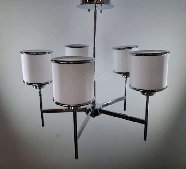 Angled view of a polished chrome five-light chandelier with white cylinder shades on a multi-arm frame.